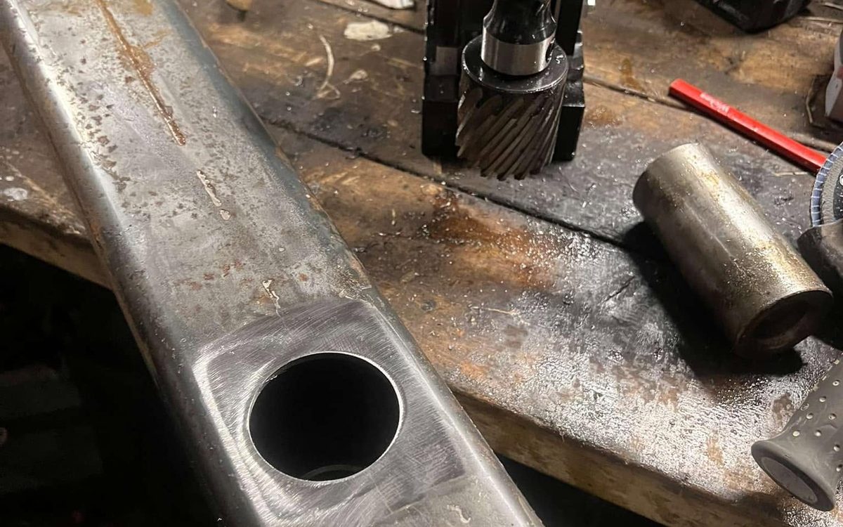 Magnetic drill cutting a bore through box section steel during a fabrication job