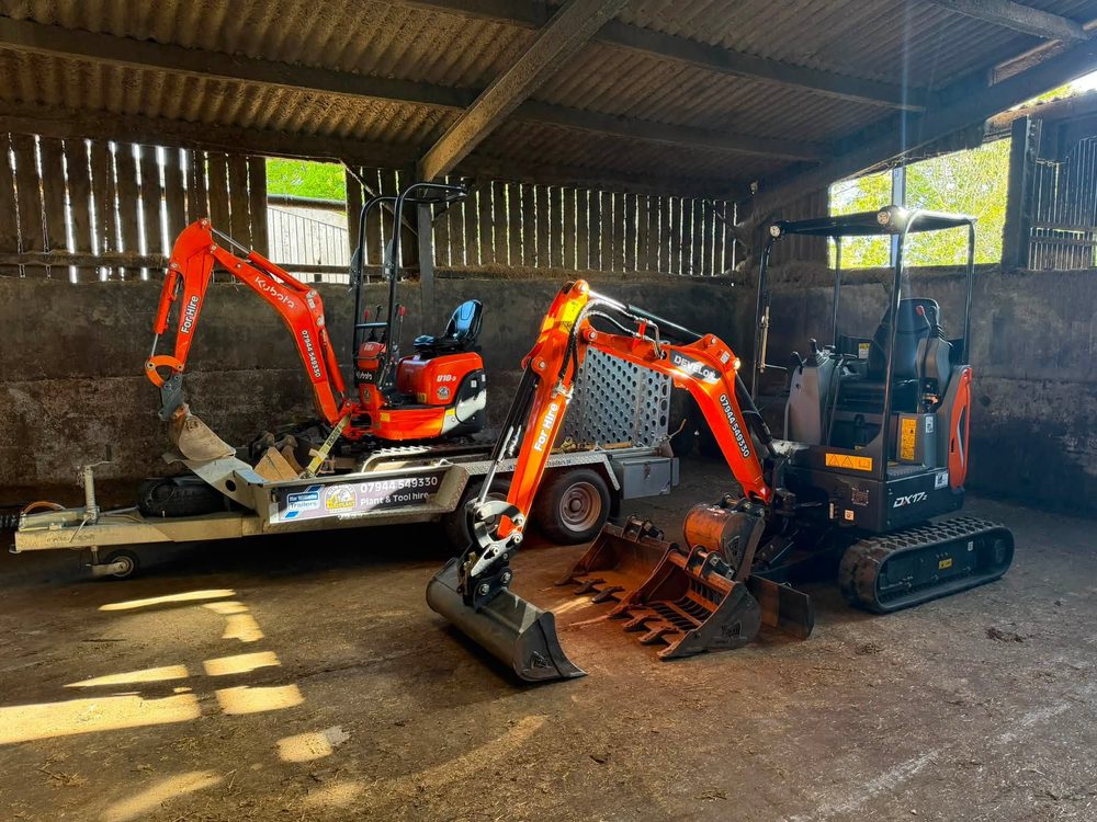 Mini excavators and a full set of buckets and attachments stored in the barn