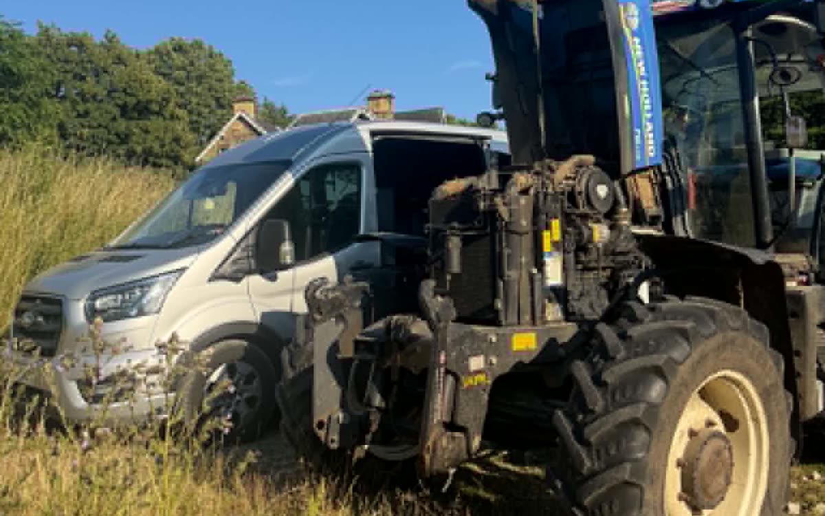 New Holland tractor with the bonnet up being repaired on farm